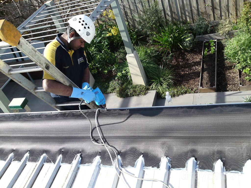 A gutter guard being customized to fit a larger box gutter.