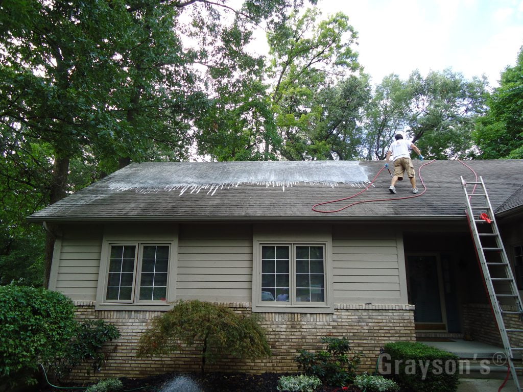 Roof cleaners using a system called "soft washing" on an asphalt roof.