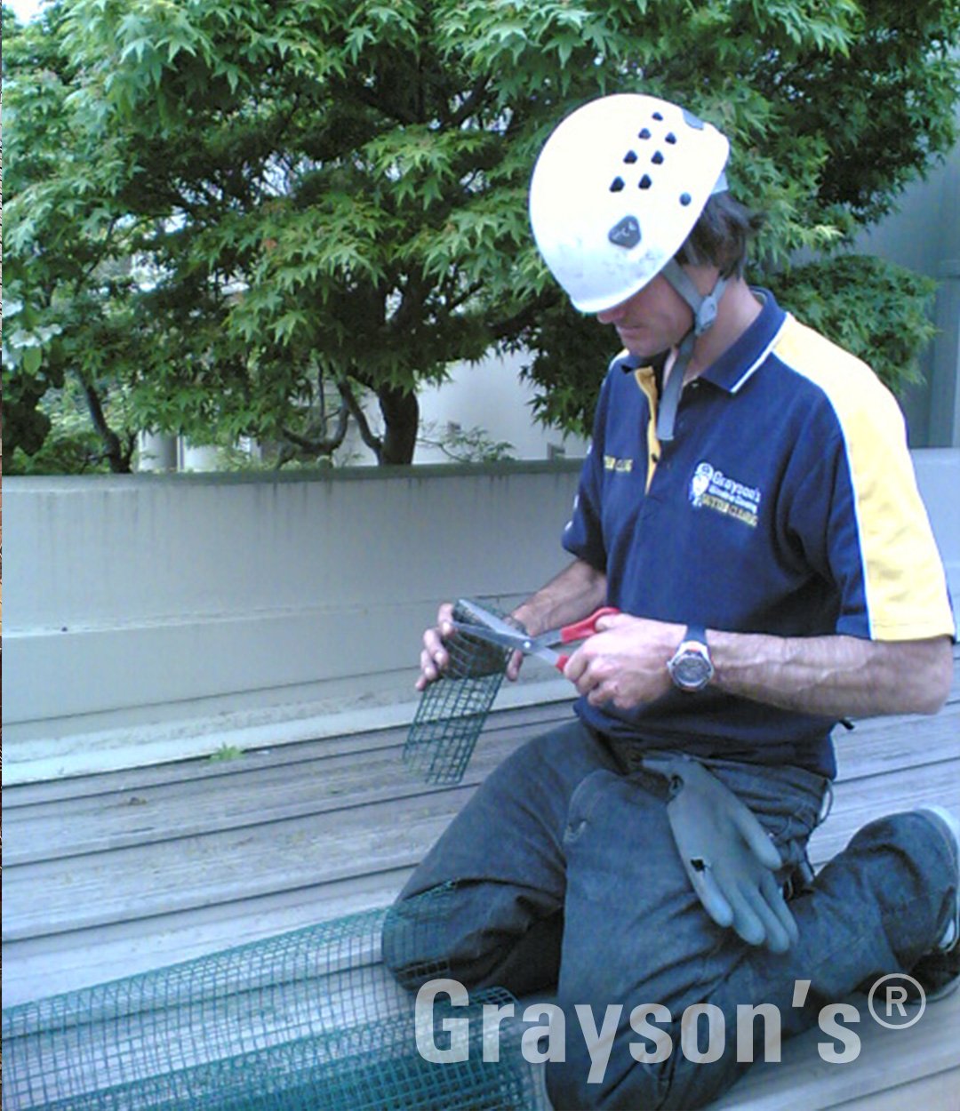 Grayson's staff on a roof cutting a custom downpipe strainer